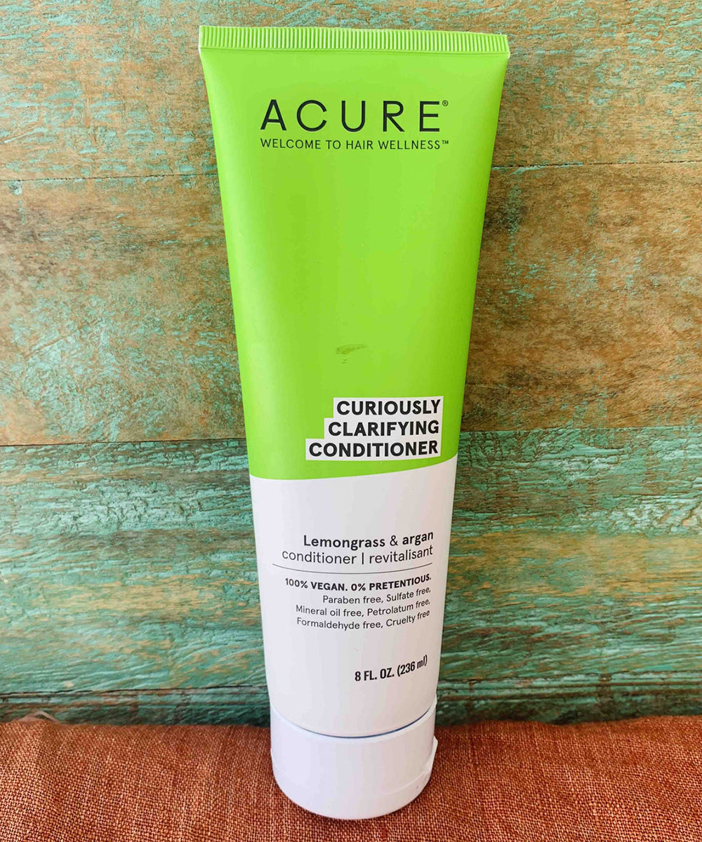 Acure Curiously Clarifying Conditioner tube on a wooden surface