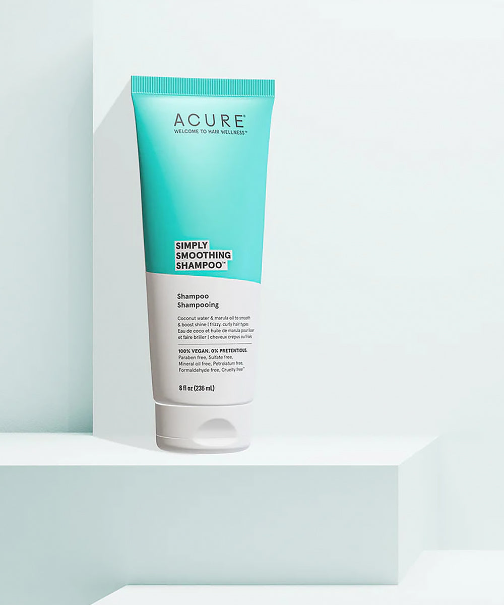 Acure Simply Smoothing Shampoo bottle on a light blue background
