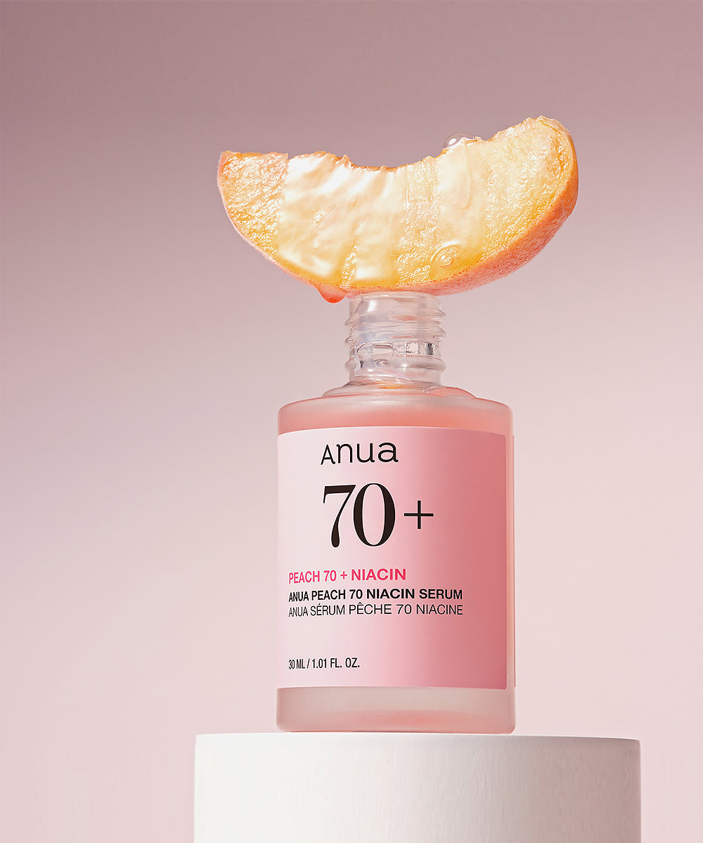 Anua 70+ skincare serum bottle with a peach slice on a pink background