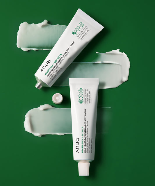 Two tubes of Anua cream on a green background with visible cream smears.