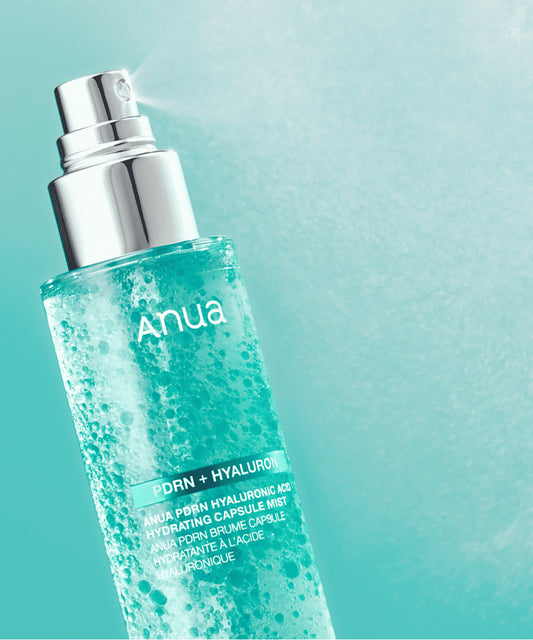 Close-up of the Anua PDRN + Hyaluron Hydrating Capsule Mist bottle spraying a fine, hydrating cloud of mist against a gradient teal background