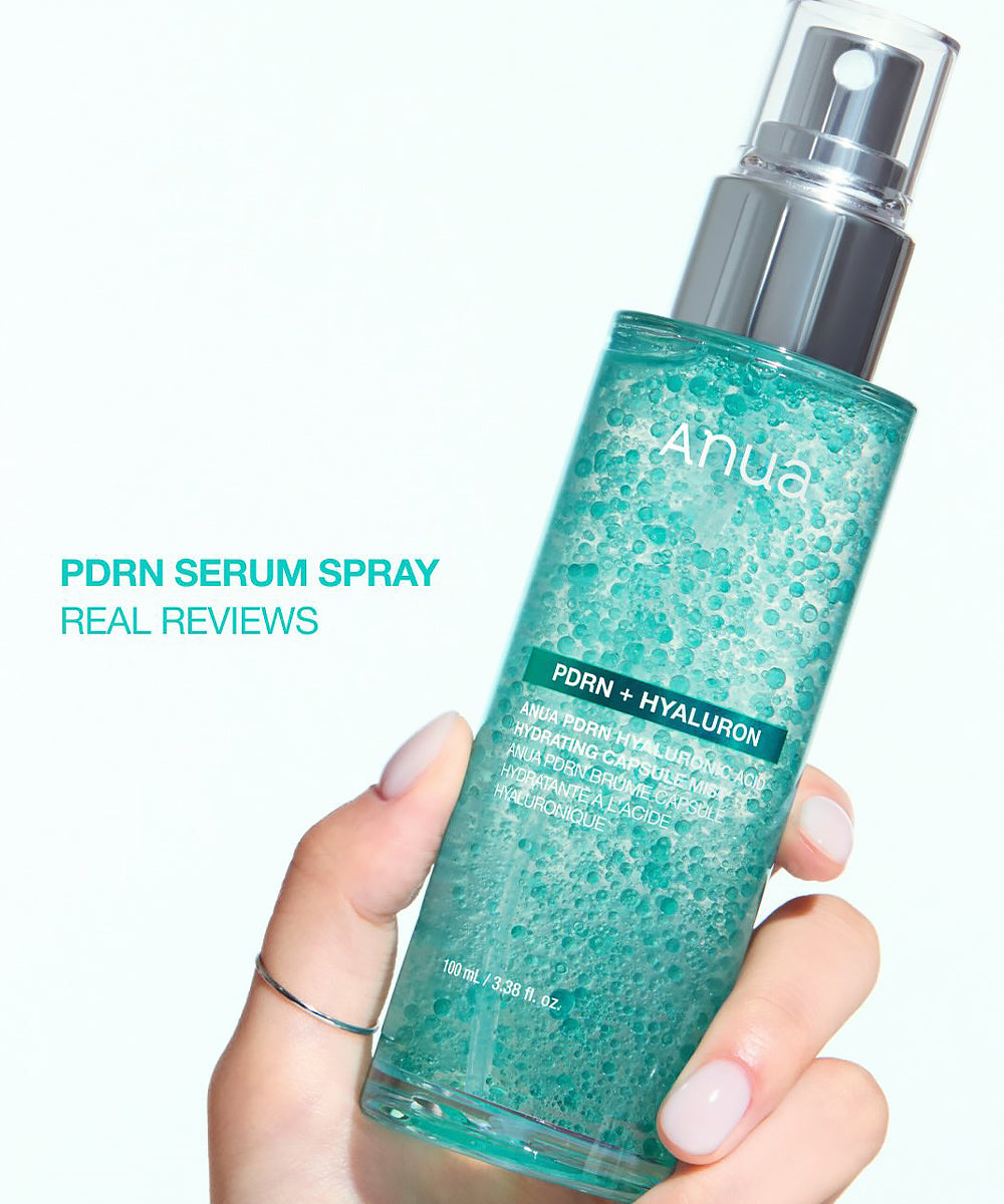A hand holding the Anua PDRN Serum Spray bottle against a bright white background, featuring the text "PDRN SERUM SPRAY REAL REVIEWS."