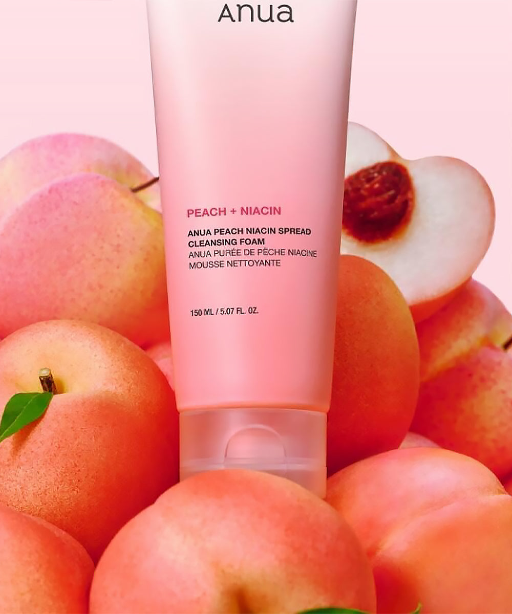 Anua Peach + Niacin cleansing foam tube surrounded by peaches on a pink background