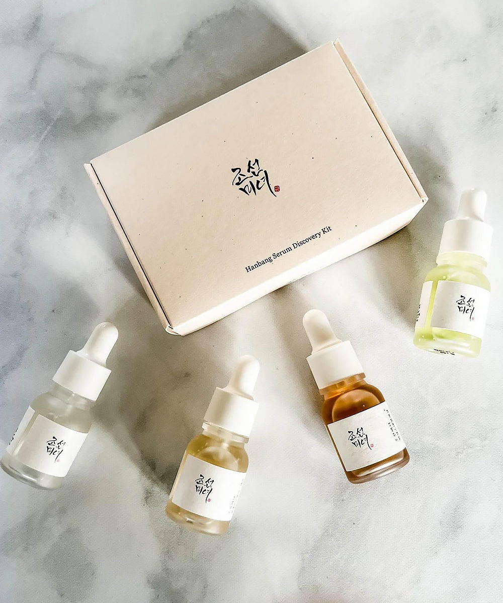 Set of skincare serum bottles with a box on a marble surface