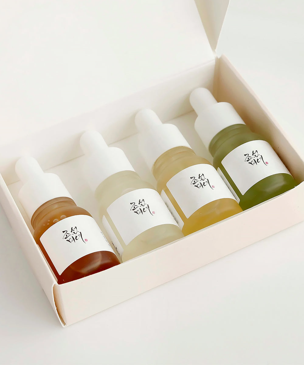 Set of four small bottles with droppers in a box on a light background
