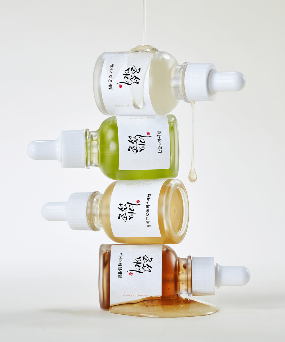 Four skincare serum bottles with droppers on a white background