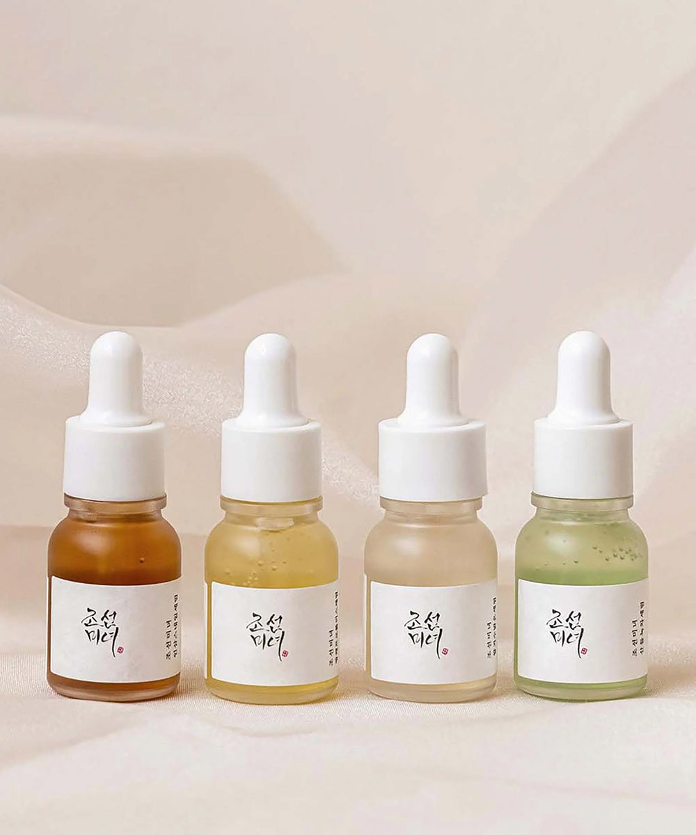 Four dropper bottles with different colored liquids on a light background