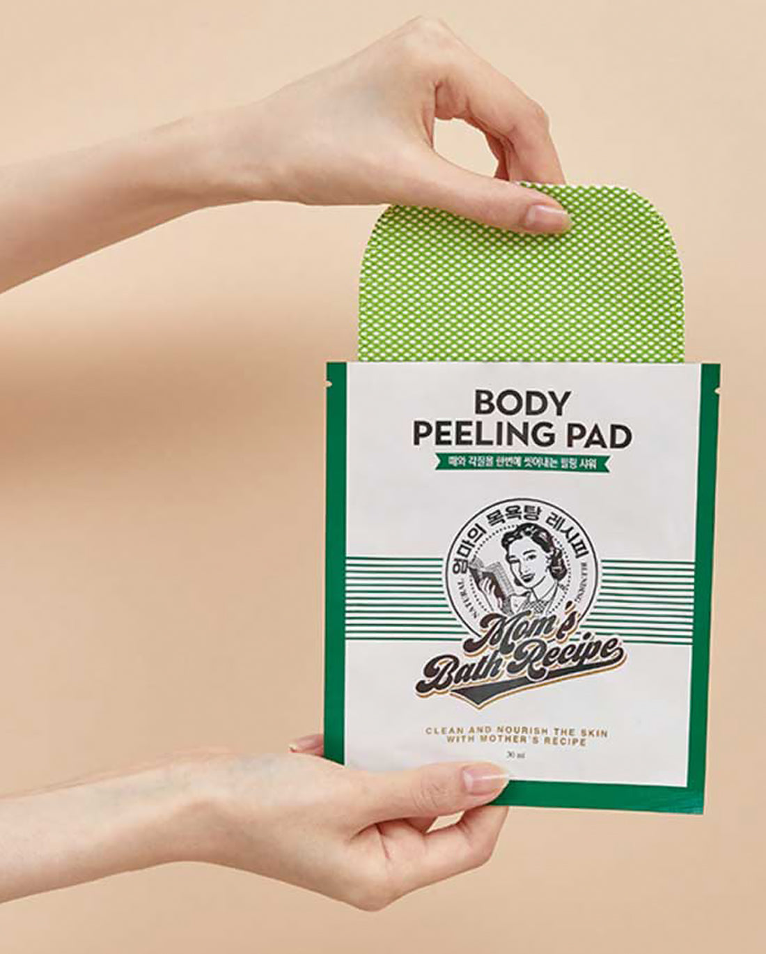 Body peeling pad packaging held by a hand against a beige background