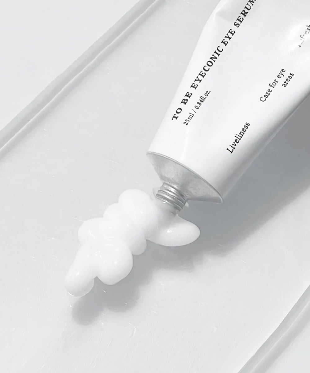 Eye serum tube with white gel being squeezed out on a light gray background