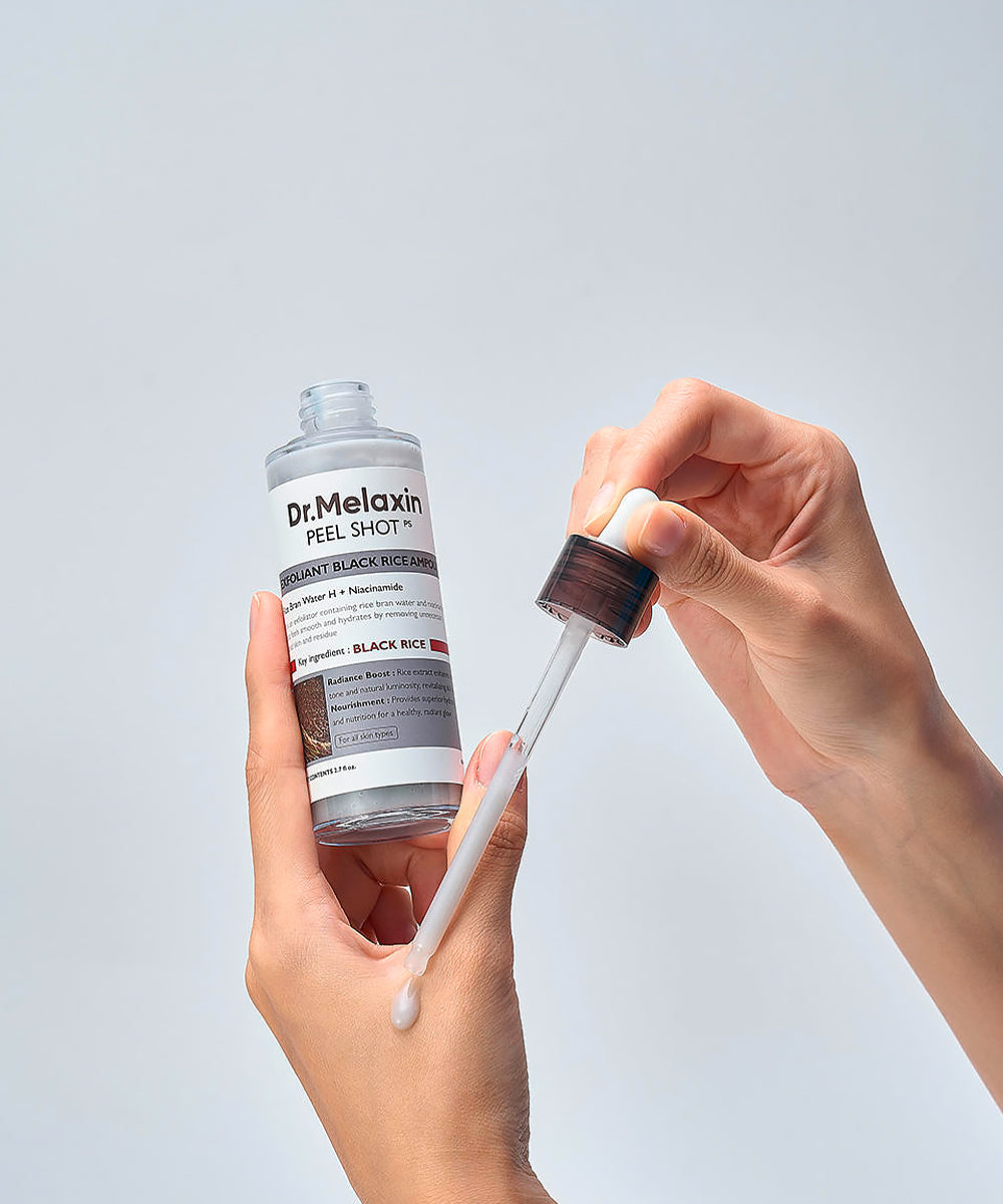 Dr. Melanin peel shot bottle with dropper held by a hand against a light gray background