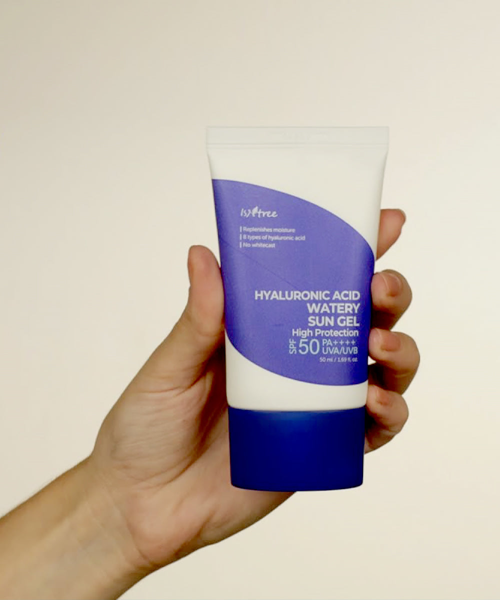 Hand holding a tube of Hyaluronic Acid Watery Sun Gel with a blue and white design.