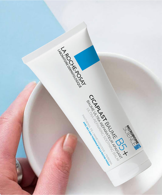 La Roche-Posay Cicaplast Baume B5+ tube held by a hand on a light blue and white background