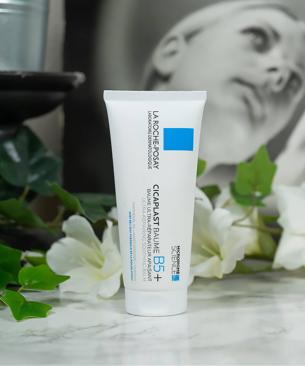 La Roche-Posay Cicalfate Baume B5+ tube on a marble surface with flowers and blurred background