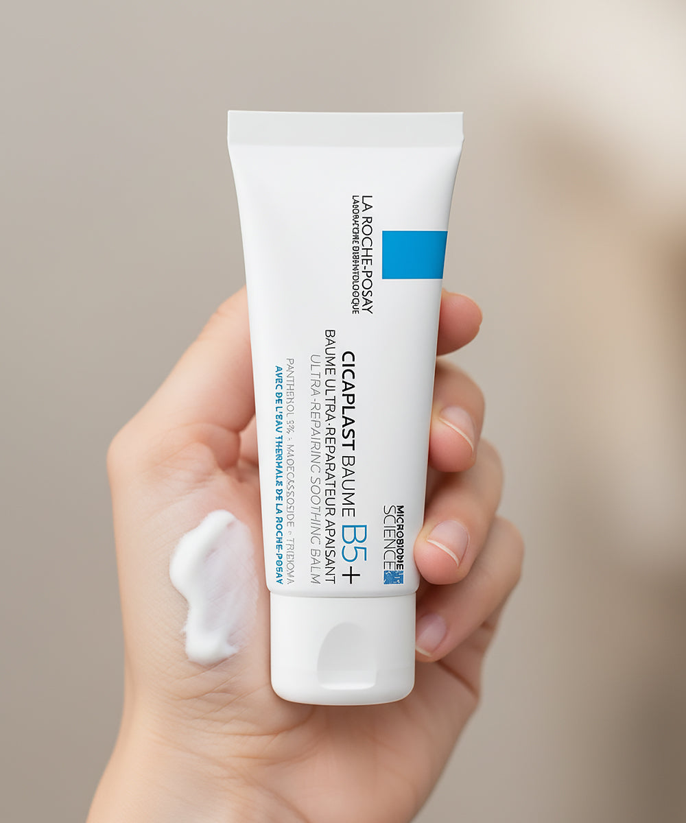 Hand holding a tube of La Roche-Posay Cicaplast Baume B5+ on a neutral background