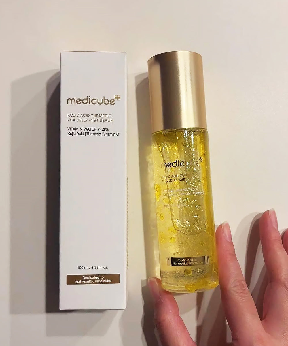 Medicube skincare serum bottle held by a hand with packaging in the background