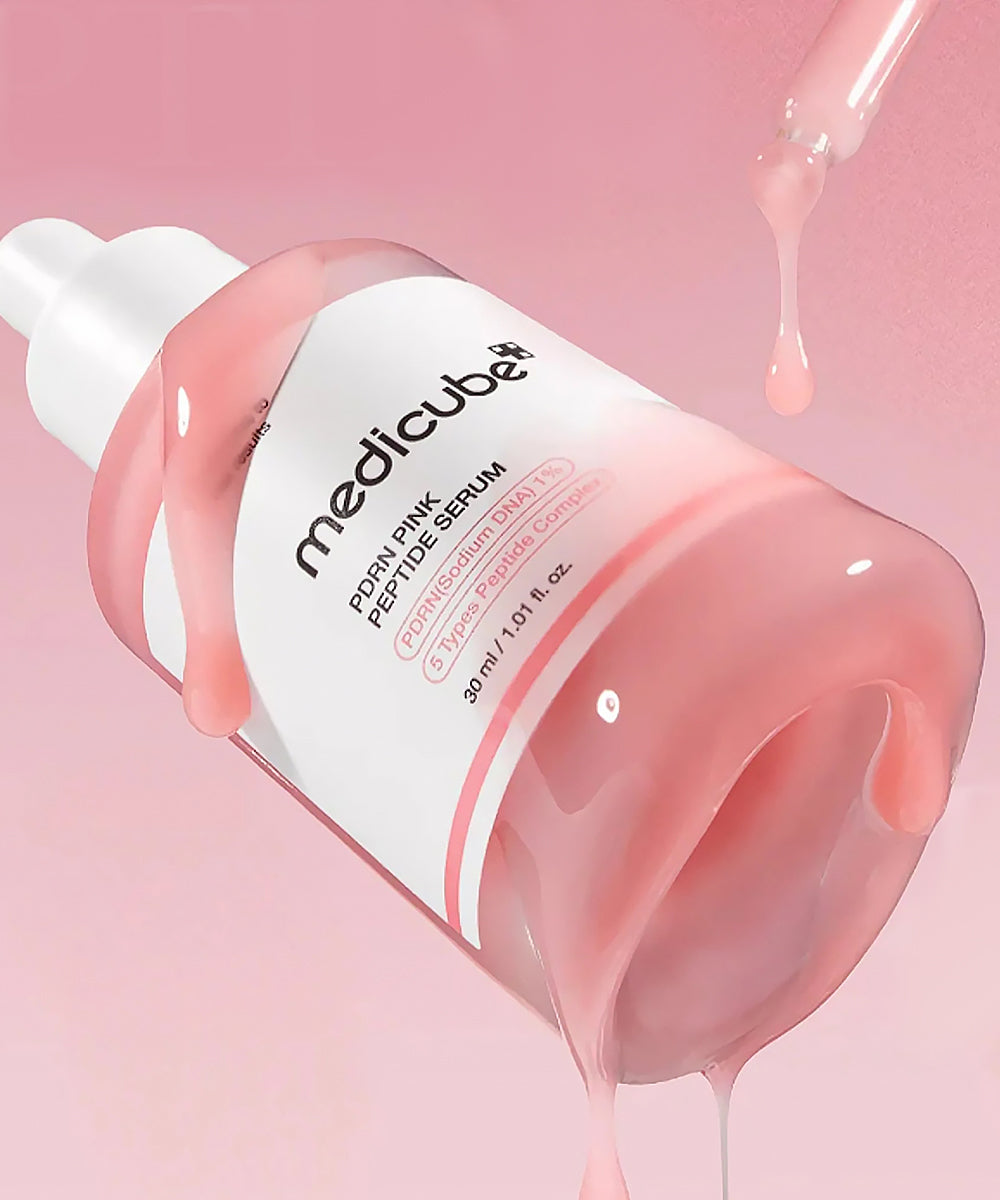 Medicube serum bottle with pink serum being dripped onto a pink background