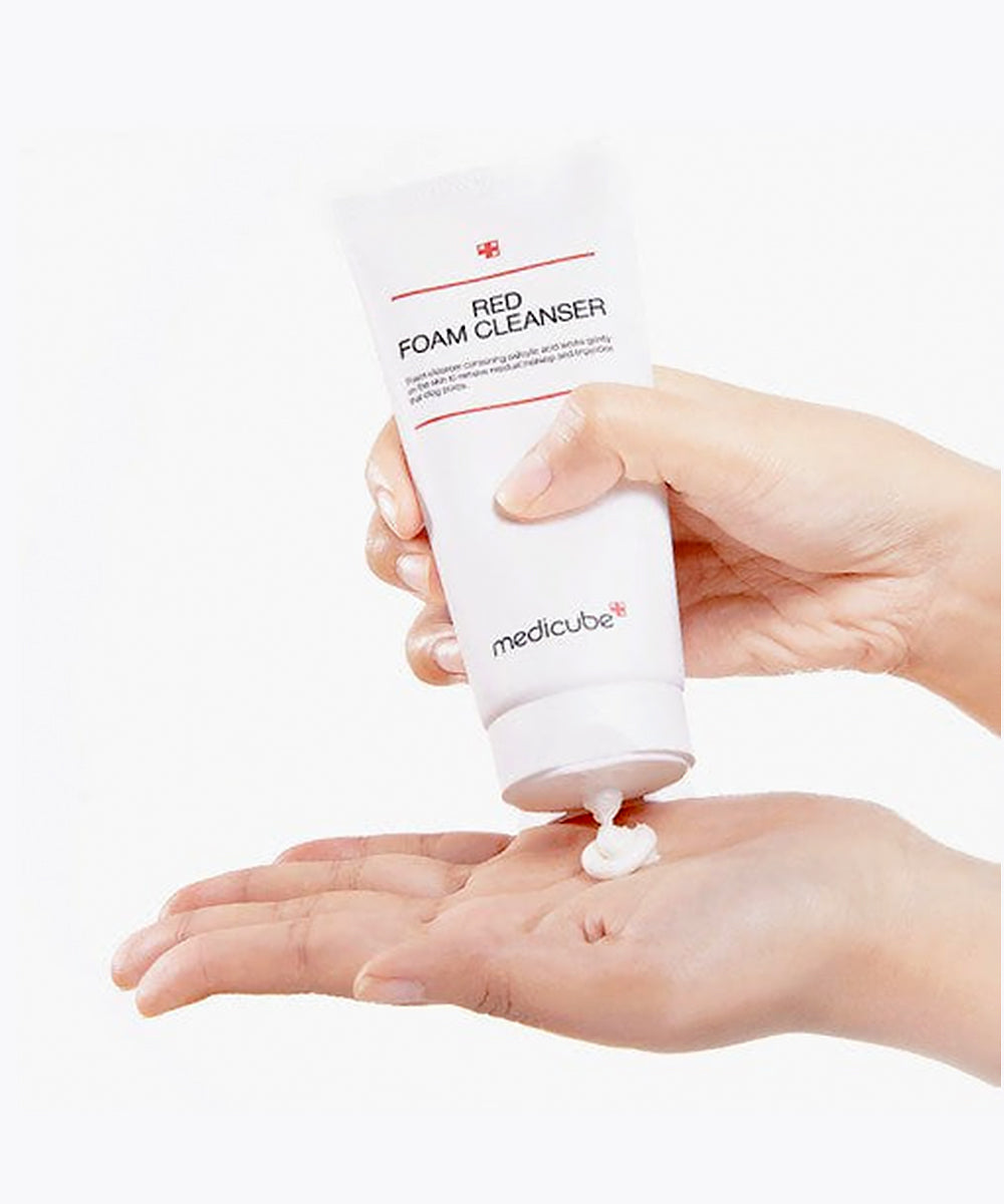 Hand holding a tube of Medicube Red Foam Cleanser with foam on palm