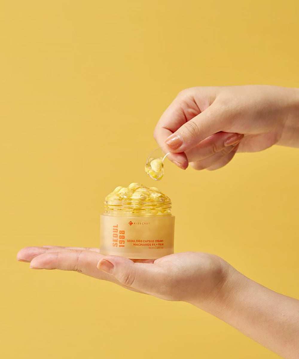 Hand holding a jar of skincare product with a yellow background