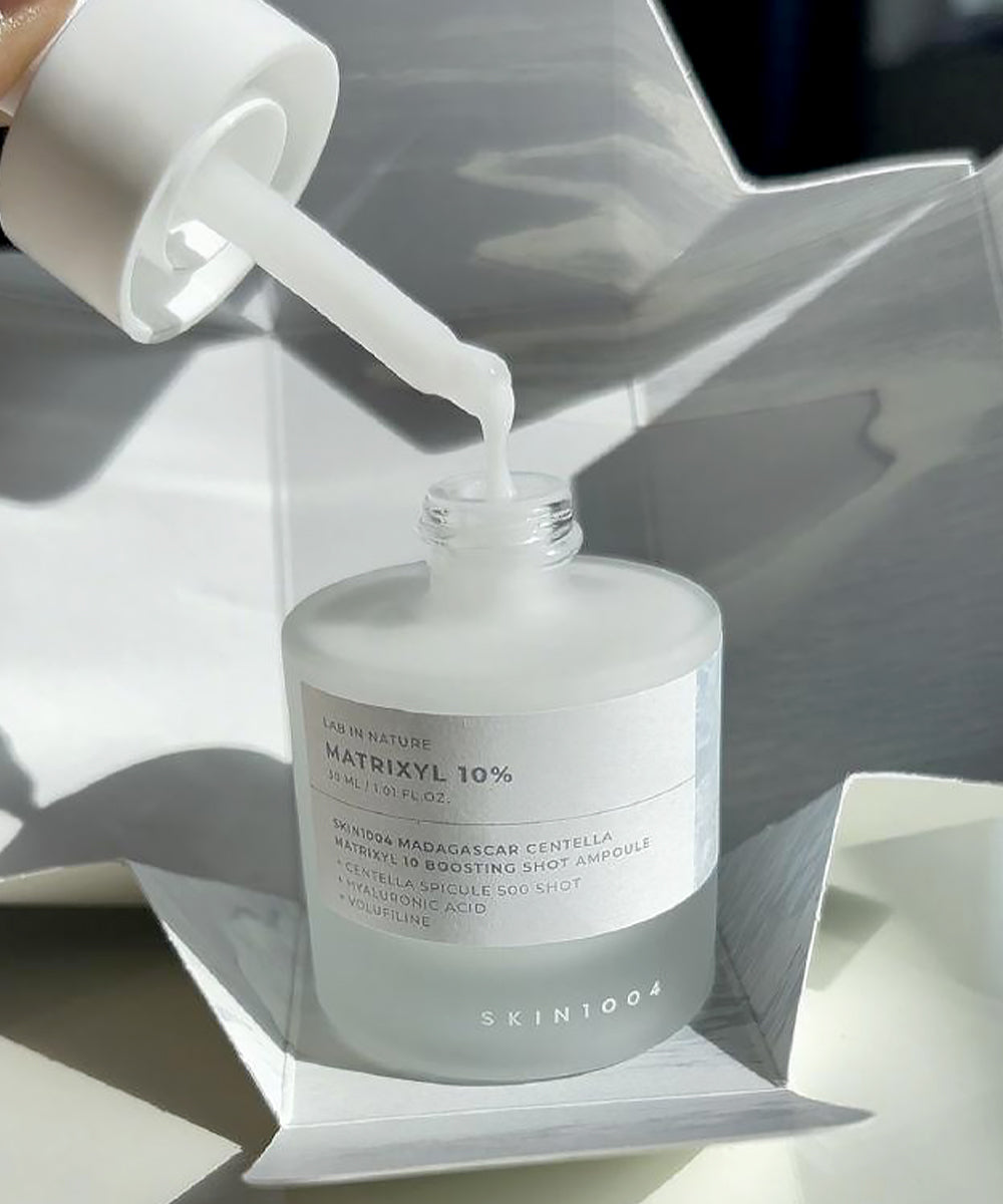 Skincare serum bottle with dropper on a reflective surface