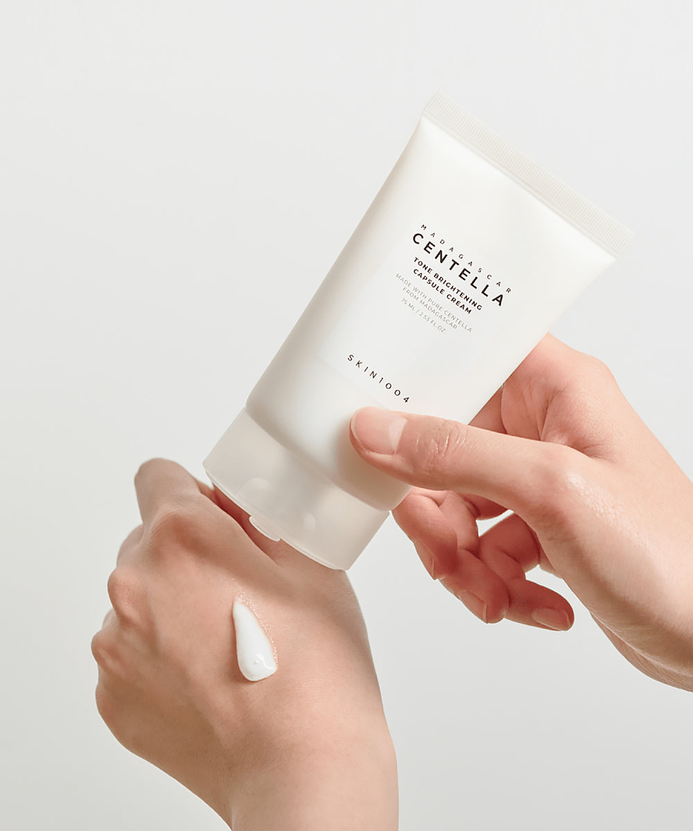 Person applying a white cream from a tube labeled 'CENTELLA' on a light background