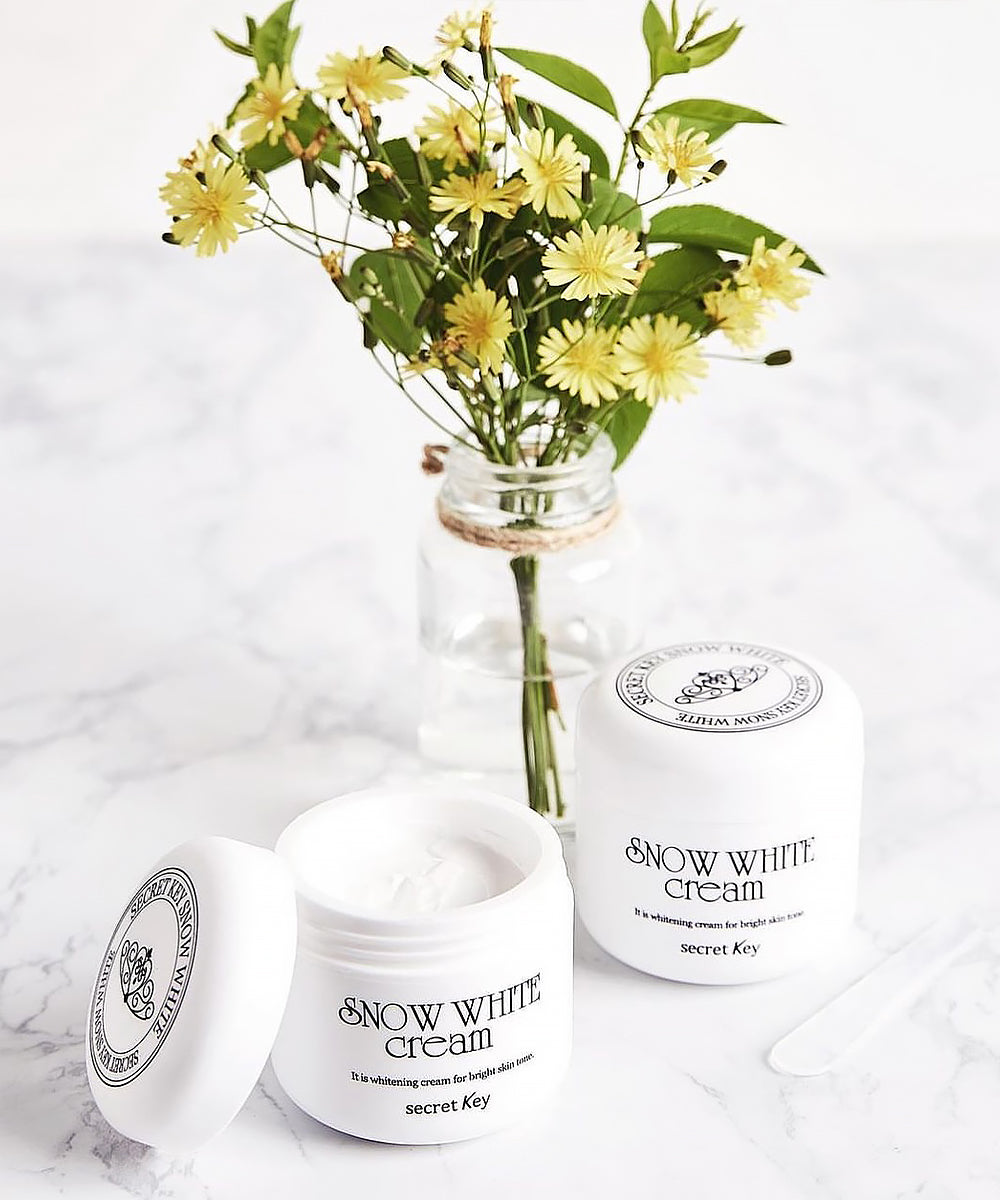 Snow White cream jars with a vase of yellow flowers on a white background