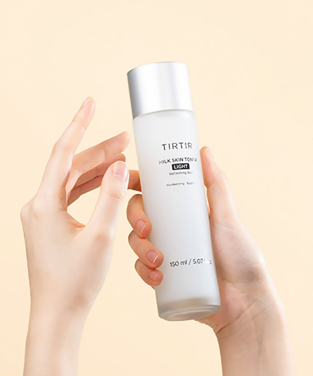 Hand holding a TIRTIR skincare bottle against a beige background