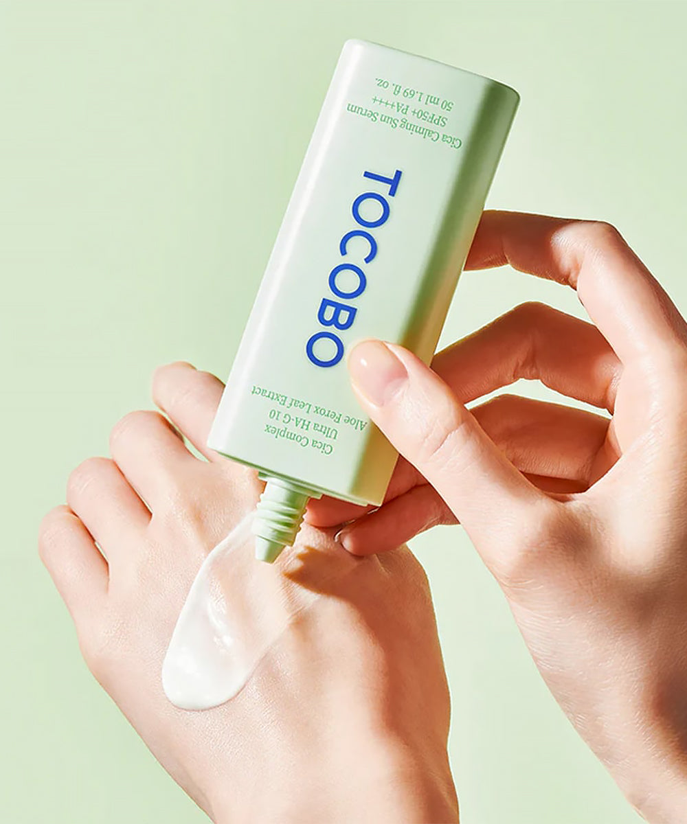 Person applying Tocobo skincare product to their hand against a light green background