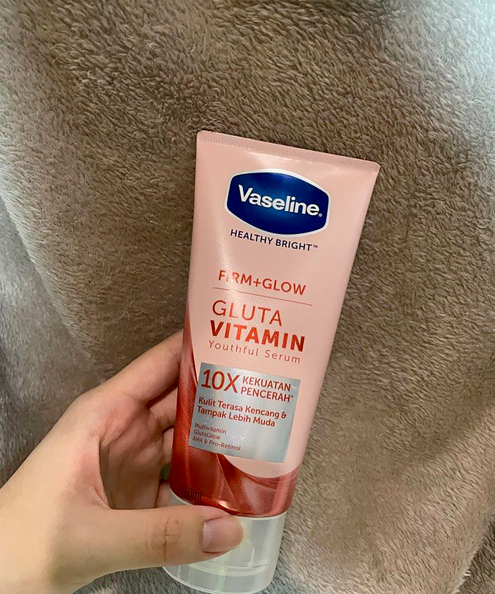 Vaseline Gluta Vitamin serum tube held by a hand on a textured surface