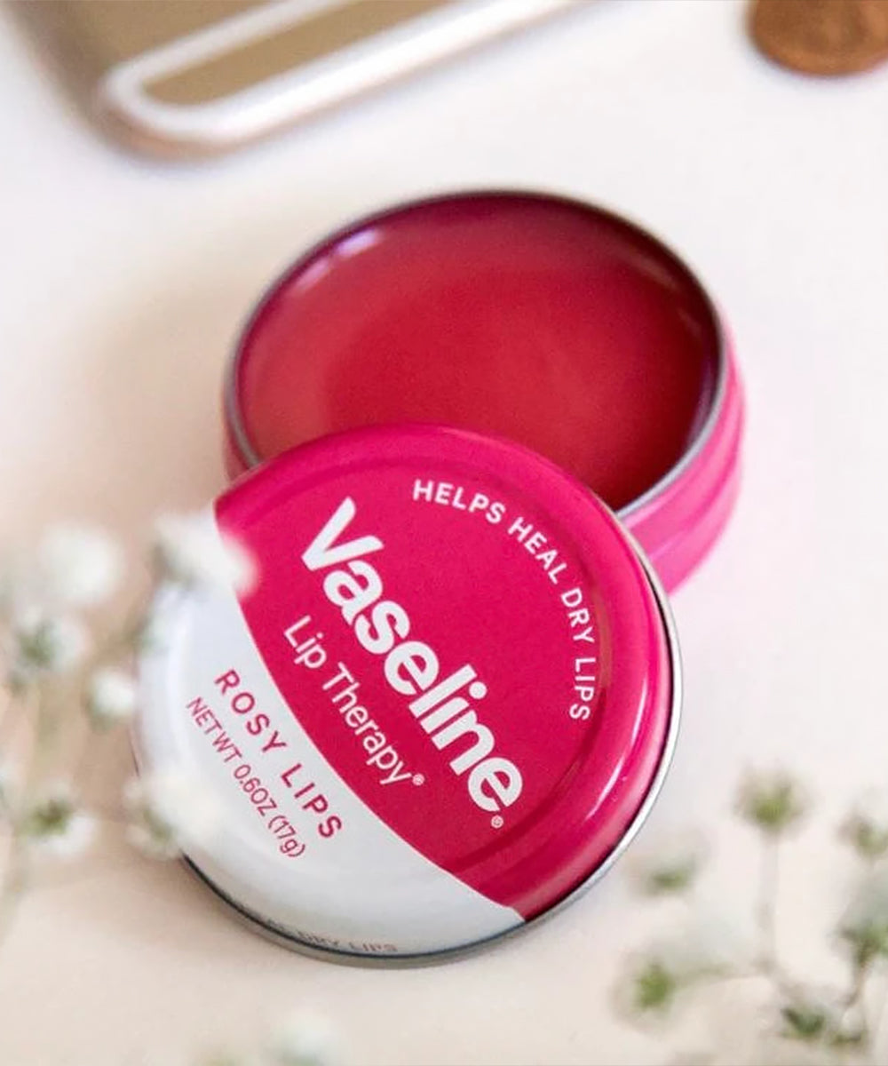 Vaseline lip balm tin with 'Rosy Lips' on a blurred background