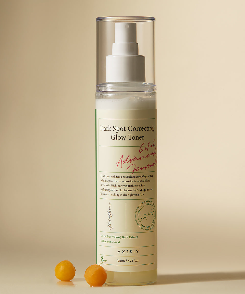 Dark spot correcting glow toner bottle with pump on a beige background
