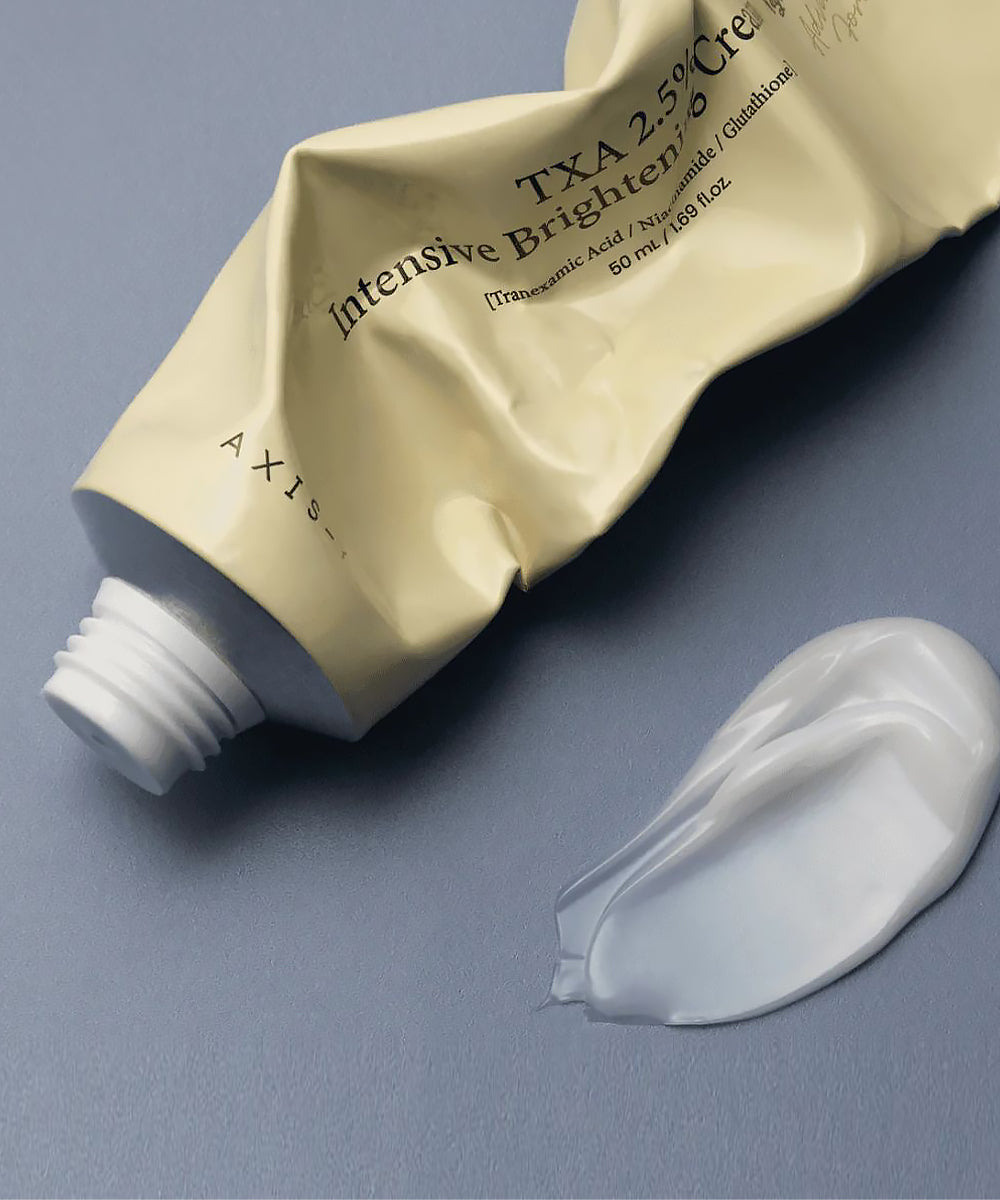 Cosmetic tube labeled 'AXIS' with a swatch of cream on a gray background