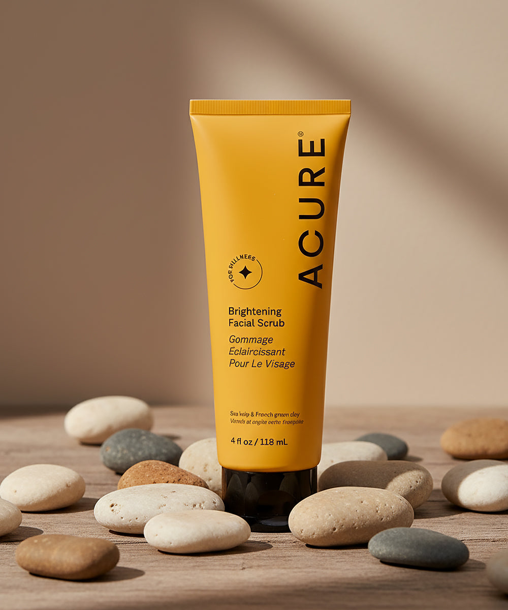 Acure brightening facial scrub tube on a wooden surface with stones