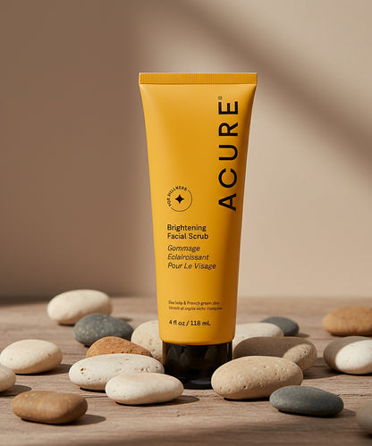 Acure brightening facial scrub tube on a wooden surface with stones
