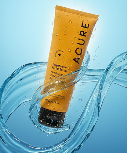 Acure facial scrub tube with water droplets on a blue background