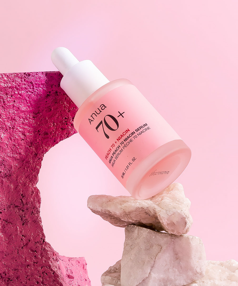 Pink skincare serum bottle with dropper on a pink and red stone background