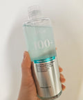 Hand holding a skincare bottle labeled 'Anua' with text on a white background