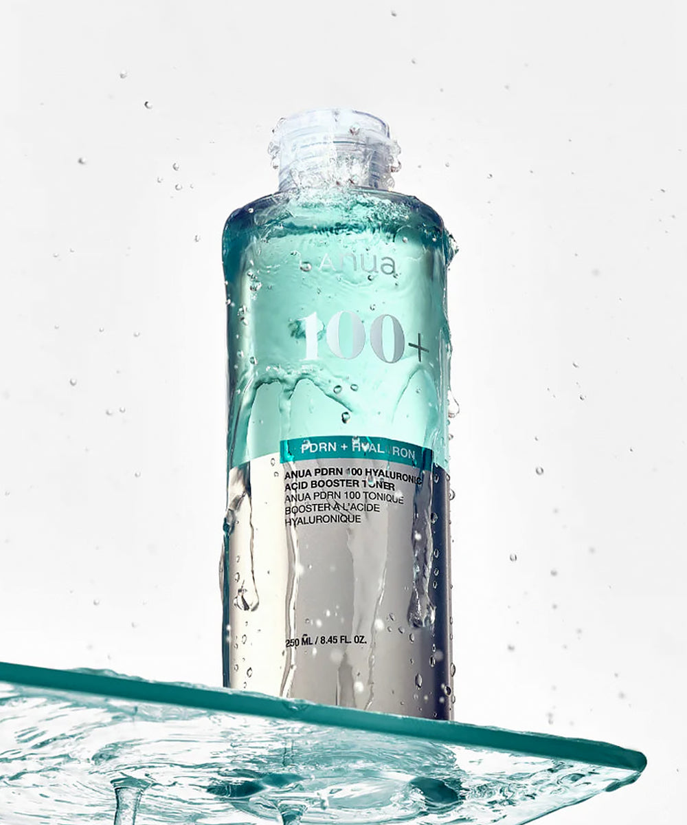 Skincare bottle with droplets on a light gray background