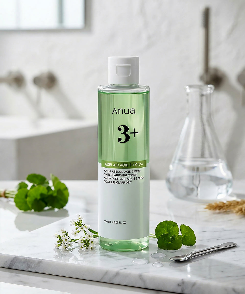 A lifestyle display of the Anua Clarifying Toner on a white marble counter, accompanied by fresh green botanicals and a glass beaker, highlighting its clean beauty aesthetic