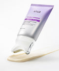 Anua Visibly Firming Collagen Retinol Hair Skin Cream in a lavender and silver squeeze tube, shown tilted with a clear gel dripping from the tip onto a smear of beige cream on a white background.