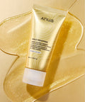 Anua Gold Wrapping Collagen Wrapping Mask in a metallic gold squeeze tube, displayed on a textured gold glitter surface.