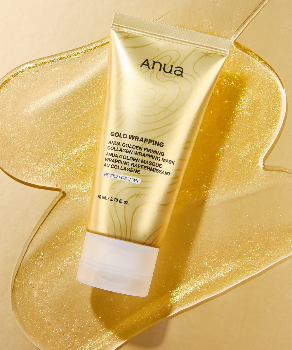 Anua Gold Wrapping Collagen Wrapping Mask in a metallic gold squeeze tube, displayed on a textured gold glitter surface.