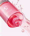 Pink bottle with liquid spilling out on a white background