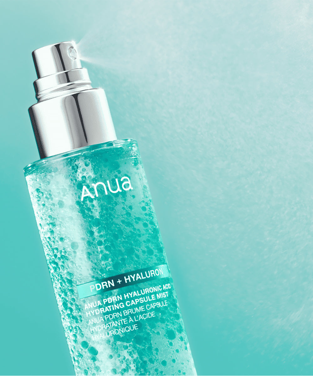 Close-up of the Anua PDRN + Hyaluron Hydrating Capsule Mist bottle spraying a fine, hydrating cloud of mist against a gradient teal background