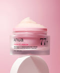 Anua Peach 77 + Niacin enriched cream jar on a pink background