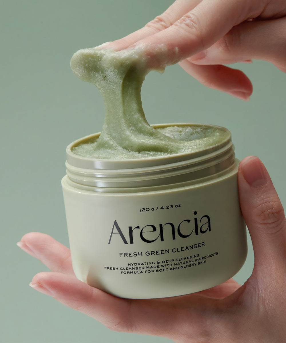 Person holding a jar of Arencia Fresh Green Cleanser with green foam.