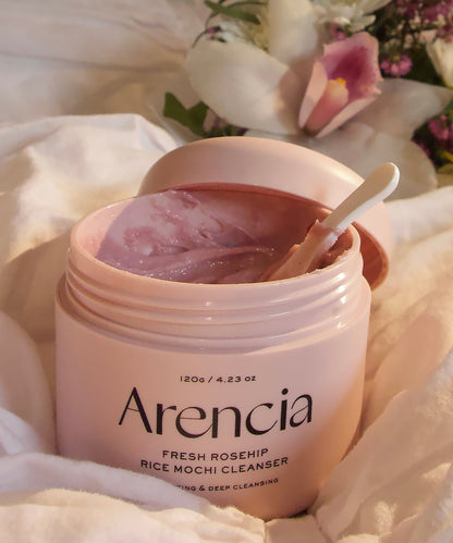 Pink jar of Arencia cleanser with a spoon on a soft white background