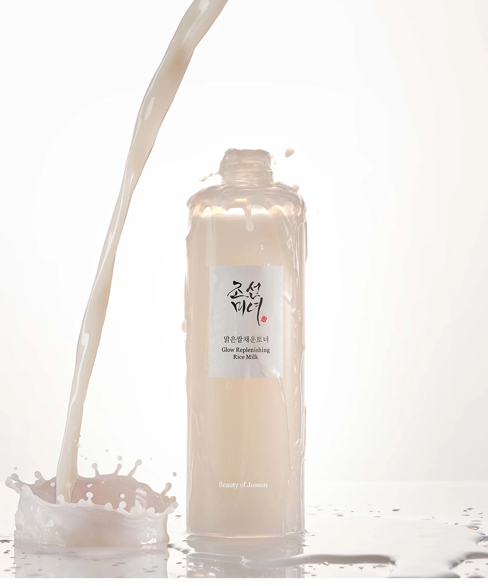 Bottle of skincare product with a label, surrounded by splashes of liquid on a white background