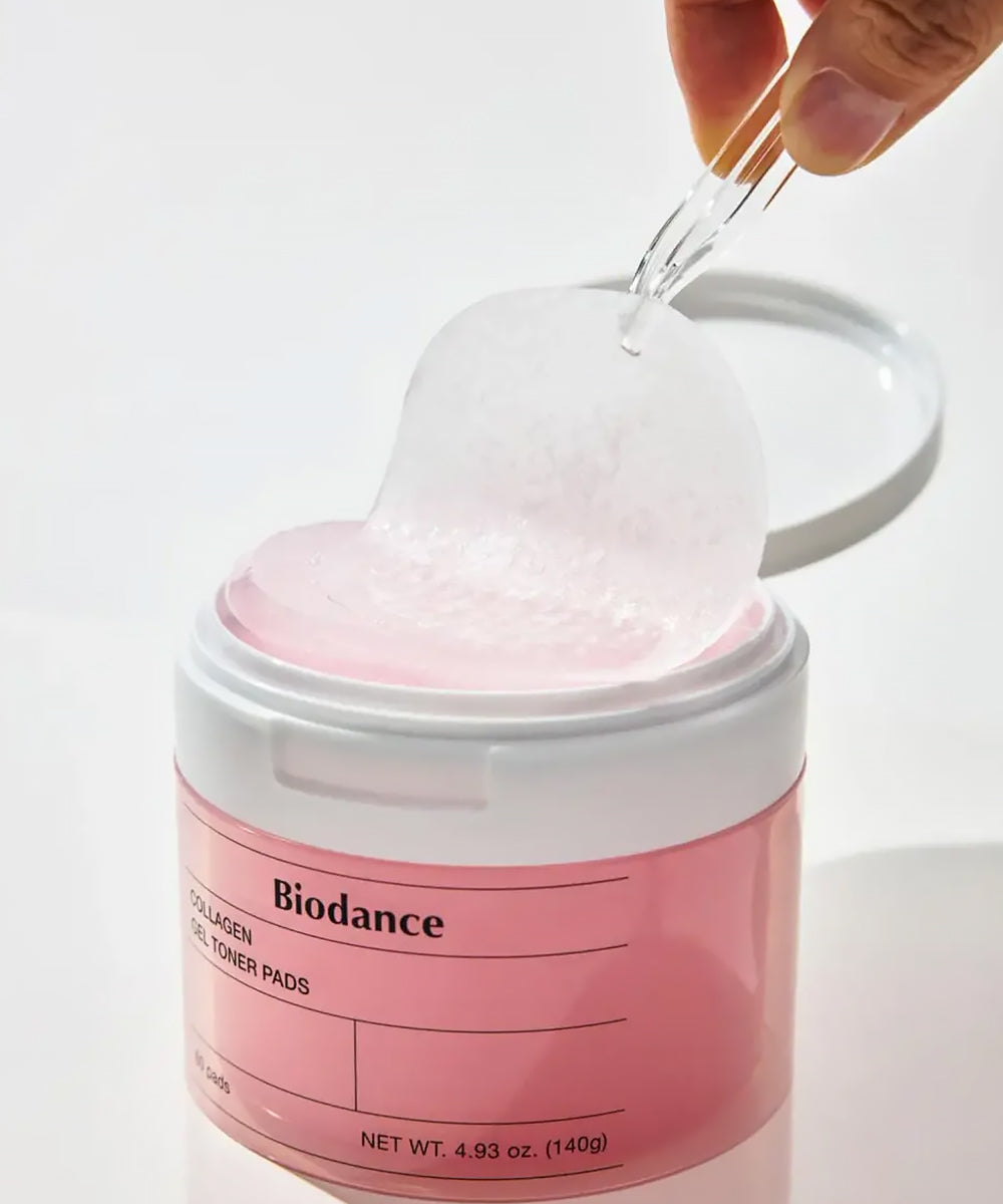 Pink jar of Biodance toner pads with a hand pouring liquid into it against a white background