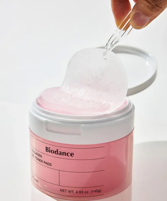 Pink jar of Biodance toner pads with a hand pouring liquid into it against a white background