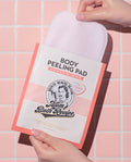 Body peeling pad with 'Mom's Bath Recipe' packaging held by a hand against a tiled wall background.